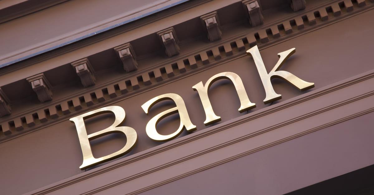  The image shows a close-up of a bank sign in gold letters against a brown background, illustrating the search query 'Central banks commercial banks and speculators in currency markets'.